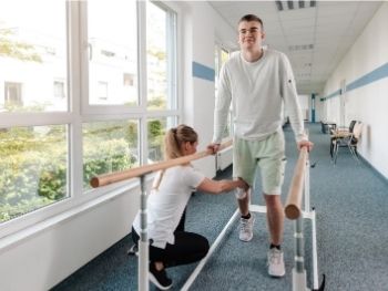 man-using-assistive-device-to-move-with-rehabilitation-specialist